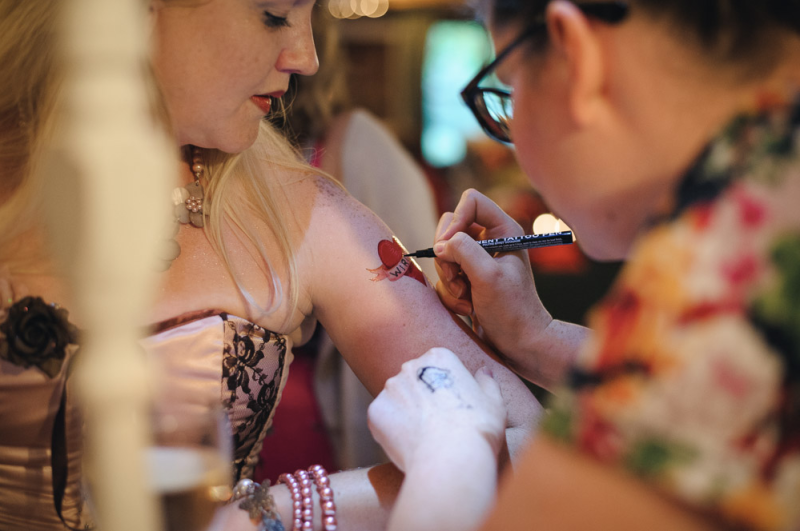 In questa foto idee per matrimonio intrattenimento: la Tattoo Station con tatuatrice professionista che disegna un cuore sul braccio di un'invitata