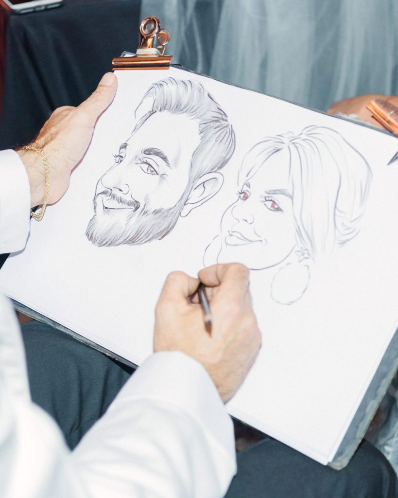 In questa foto idee per matrimonio intrattenimento: un vignettista esegue la caricatura di due invitati