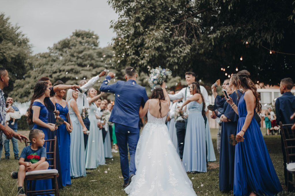 In questa foto due sposi di spalle tra gli ospiti che lanciano petali all'uscita della location per matrimonio civile