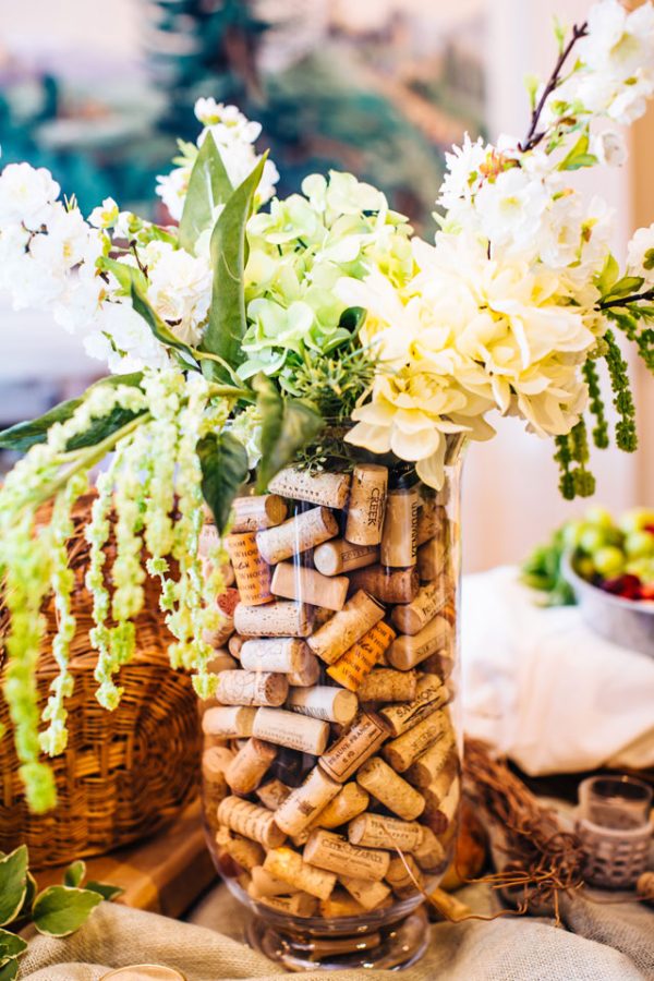 In questa foto un'idea di centrotavola matrimonio a tema vino con tappi di sughero e fiori colore bianco