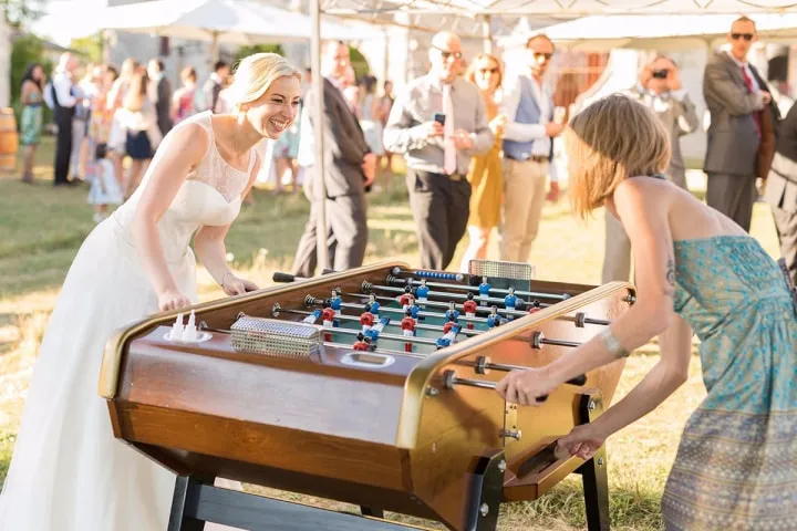 In questa foto una sposa e un'invitata giocano a calcio balilla