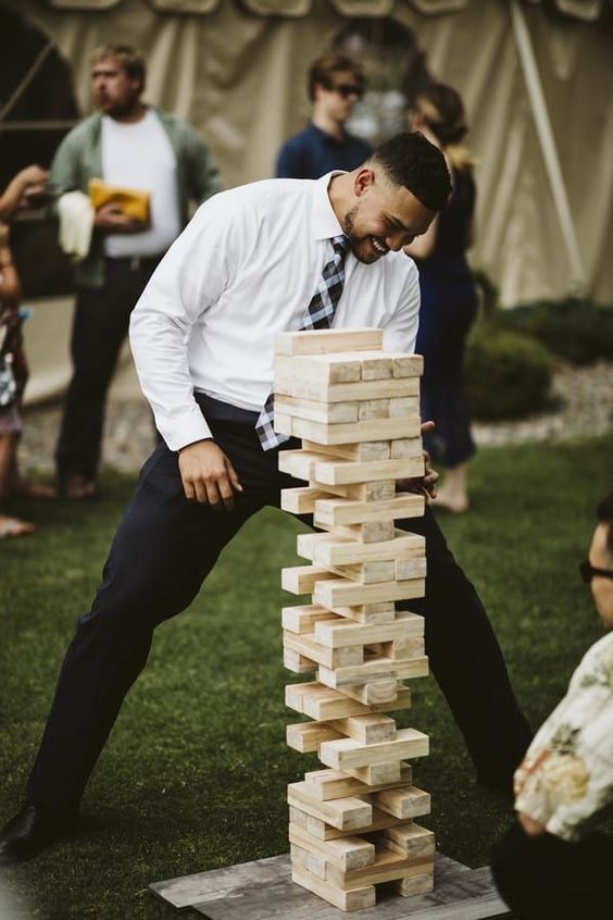 In questa foto l'invitato di un matrimonio gioca a Jenga sul prato