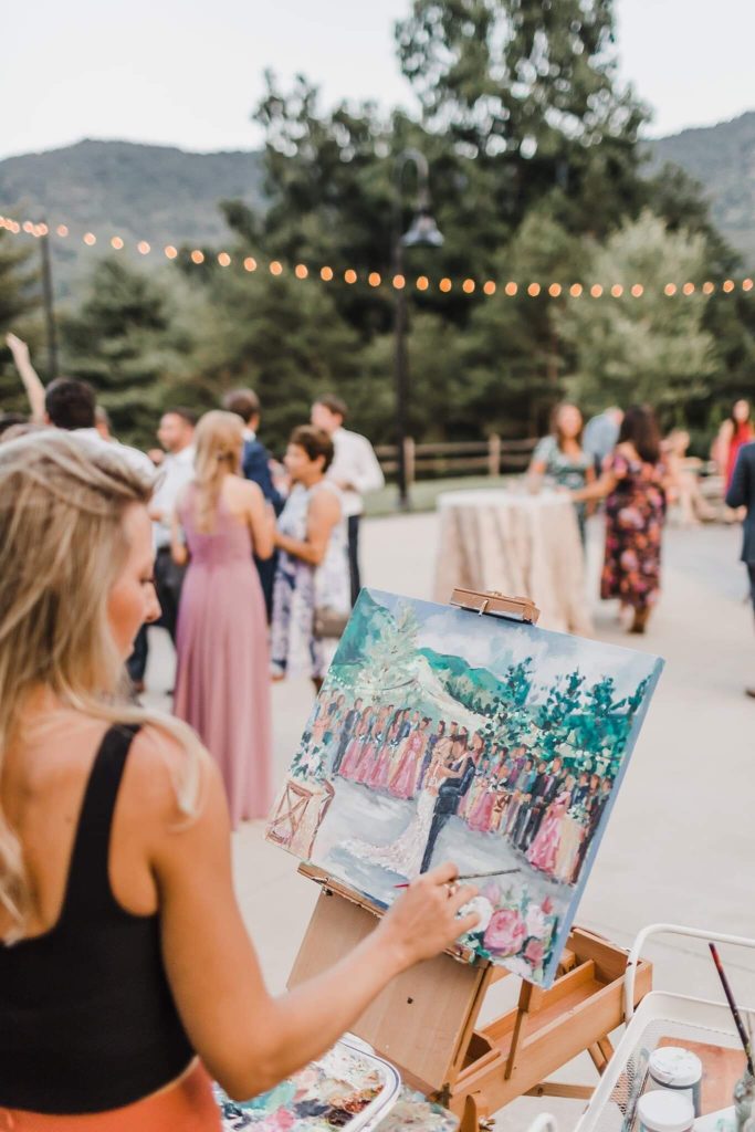 In questa foto un esempio di intrattenimento di nozze: una pittrice di Live Painting mentre dipinge il primo ballo degli sposi su un quadro posto su un cavalletto