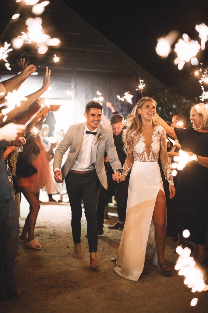 In questa foto due sposi camminano sorridenti tra le stelline luminose accese dagli invitati