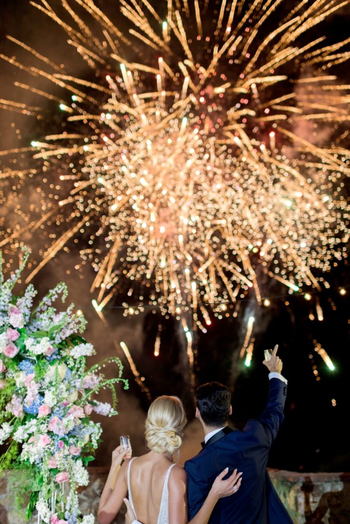 In questa foto due sposi di spalle mentre guardano uno spettacolo di fuochi di artificio