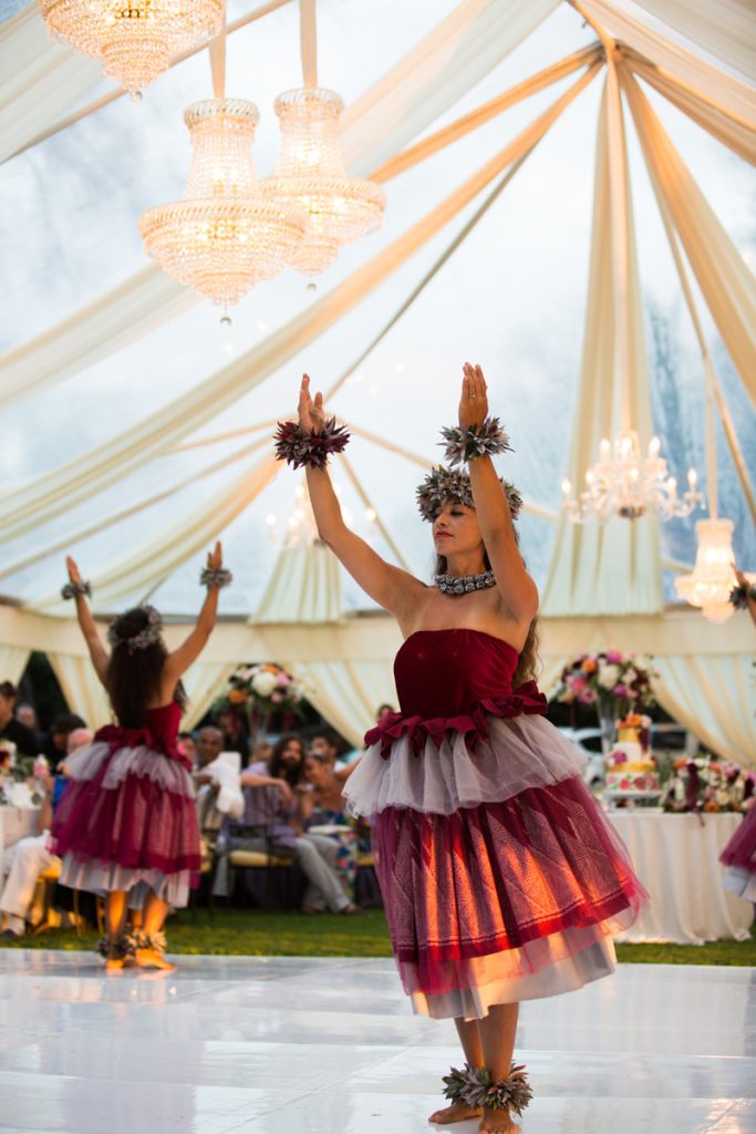 In questa foto due ballerine di hula danzano ad un matrimonio sotto un tendone bianco allestito su un prato