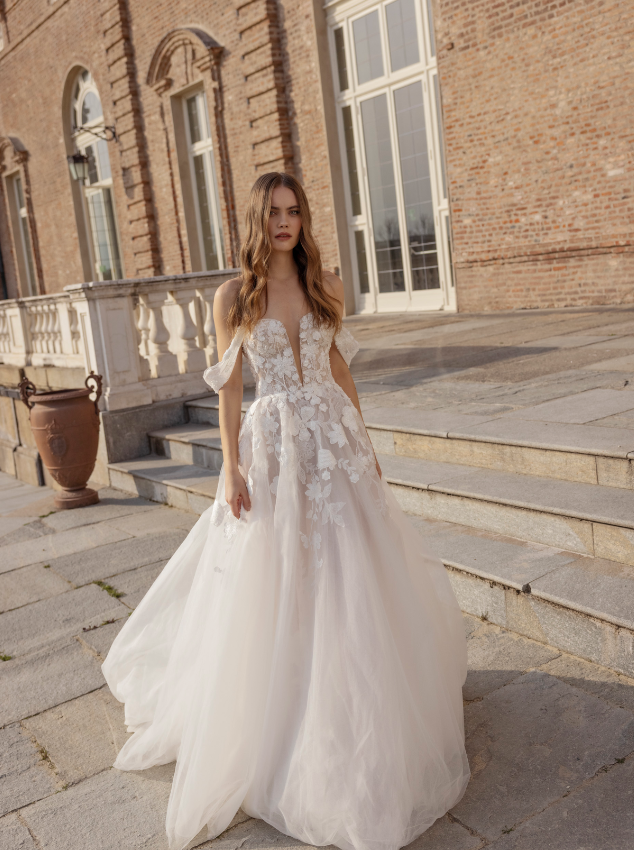In questa foto la modella indossa un abito da sposa romantico 2023 con gonna di tulle con fiori e scollo a V