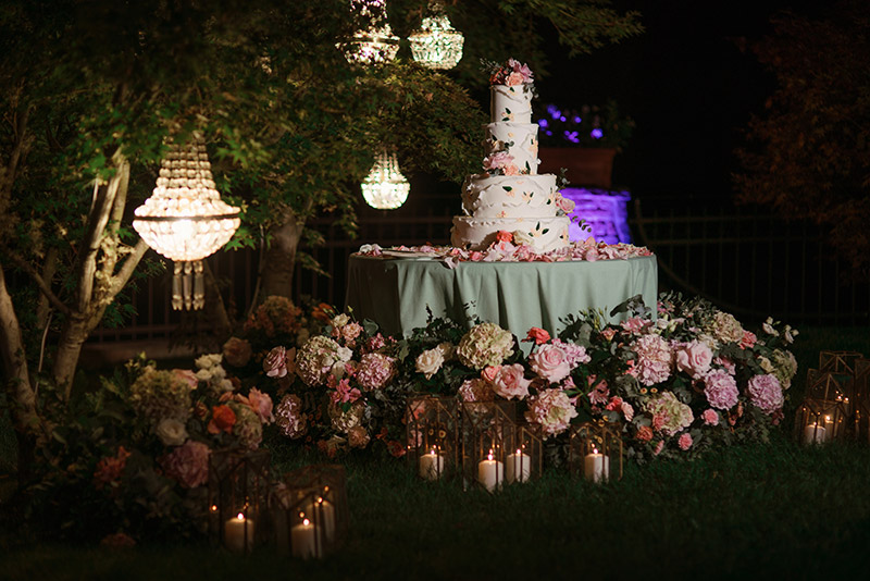 in questa foto l'elegante torta nuziale. Lo sweet table è circondato da fiori, candele e chandelier di cristallo