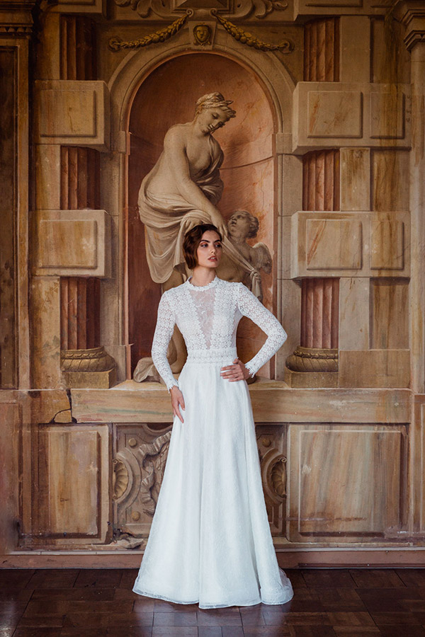 Un abito da sposa Giuliani Couture 2023, in pizzo macramè. Linea morbida, leggermente ad A, maniche lunghe e profondo scollo con sensuali trasparenze