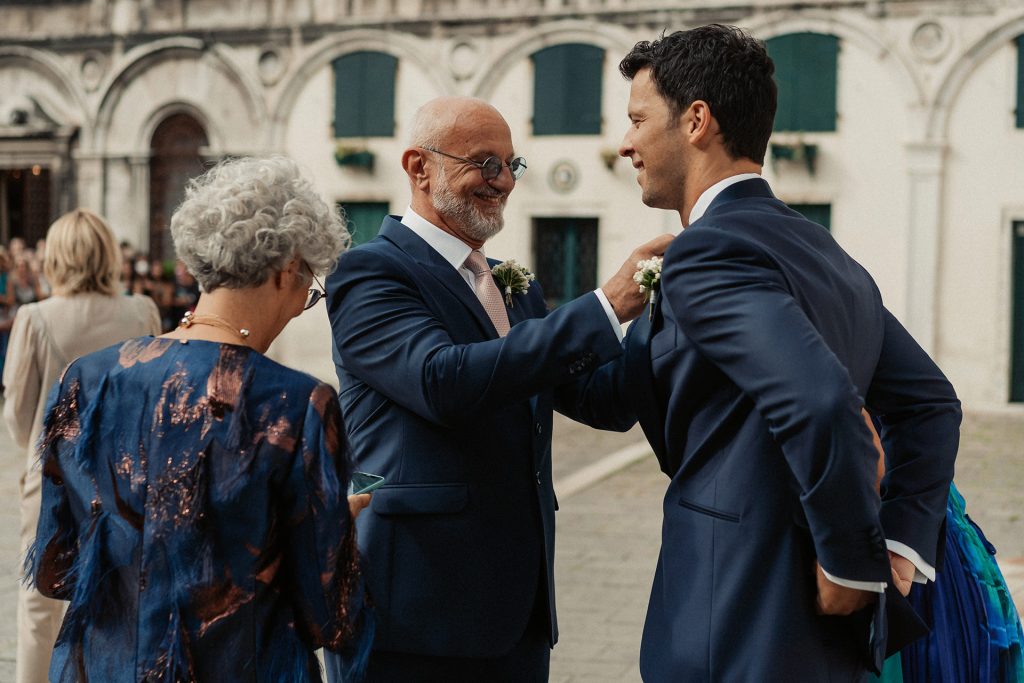 In questa foto Matteo Giunta insieme ai genitori: il papà sistema la cravatta allo sposo