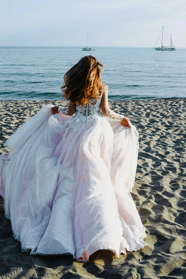 In questa foto una sposa sulla spiaggia mentre corre verso il mare