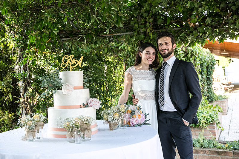 In questa foto gli sposi davanti alla torta nuziale, a tre piani e allestita in stile country chic 