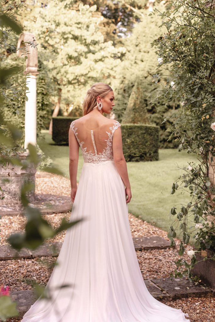 In questa foto un abito da sposa di Justin Alexander in chiffon di setacon scollatura omerale su un corpetto in pizzo rebrodè e applicazioni di cristalli