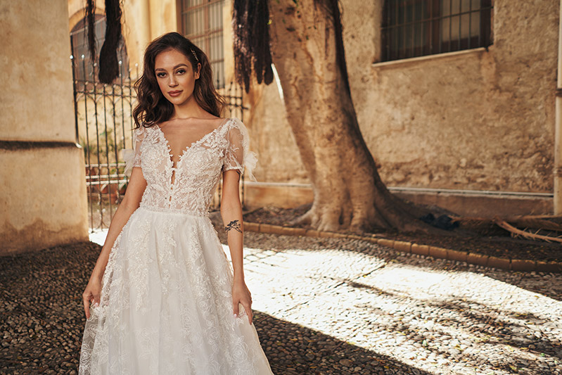 In questa foto una modella indossa un abito da sposa scivolato di Annais Bridal con ricami in pizzo all-over
