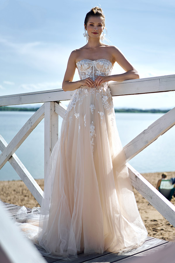 In questa foto una modella indossa un abito da sposa scivolato in tulle color cipria con corpetto a cuore steccato, decorato con ricami floreali 3D e ramage sulle lunghezze