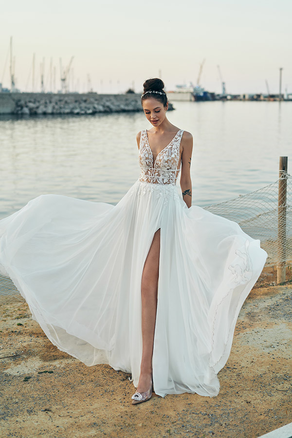 In questa foto una modella indossa un abito da sposa Annais Bridal 2023 con gonna in chiffon con spacco e corpetto in pizzo trasparente con scollo a V