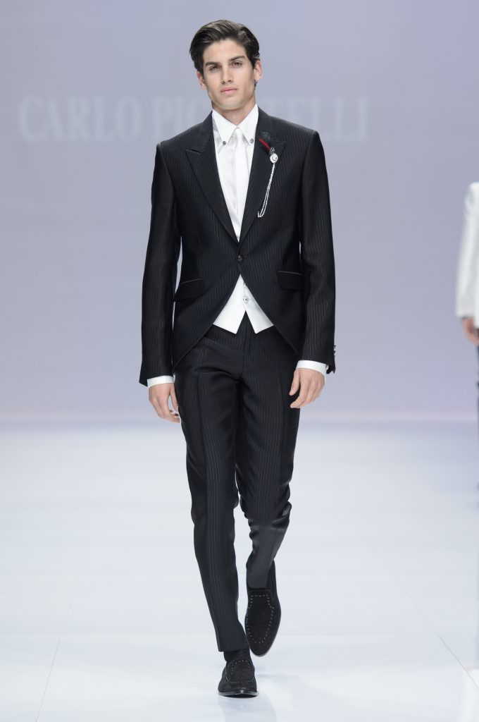 In questa foto un modello sfila indossando un mezzo tight di colore nero con gilet e cravatta a contrasto di colore bianco di Carlo Pignatelli
