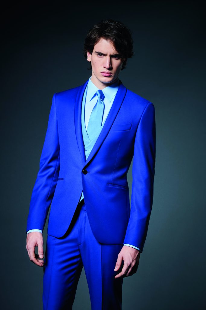 In questa foto un modello indossa un abito da sposo classico colore blu elettrico e gilet di colore turchese di Carlo Pignatelli