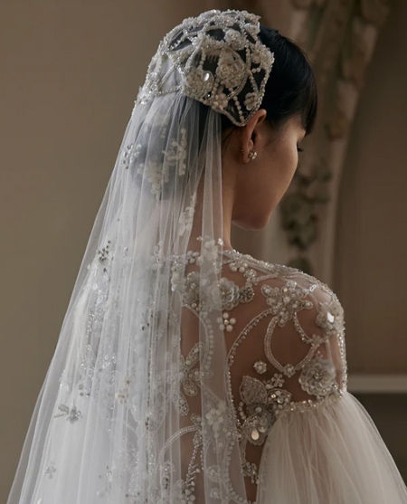 In questa foto una modella indossa un accessorio sposa 2023 un velo da sposa con fiori ricamati e perle.