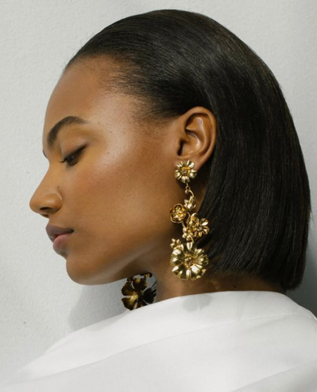 In questa foto una modella indossa degli orecchini a forma di fiori d'oro 