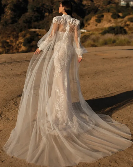 In questa foto una modella indossa una mantella da sposa con ricami Pronovias.