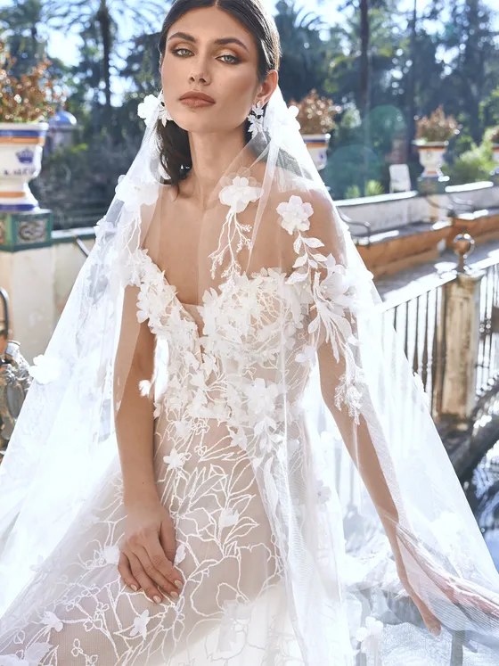 In questa foto una modella indossa un velo da sposa con con fiori ricamati.