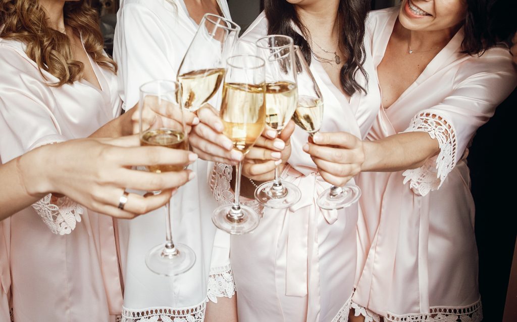 In questa foto le mani di quattro ragazze brindando con i flute durante un addio al nubilato