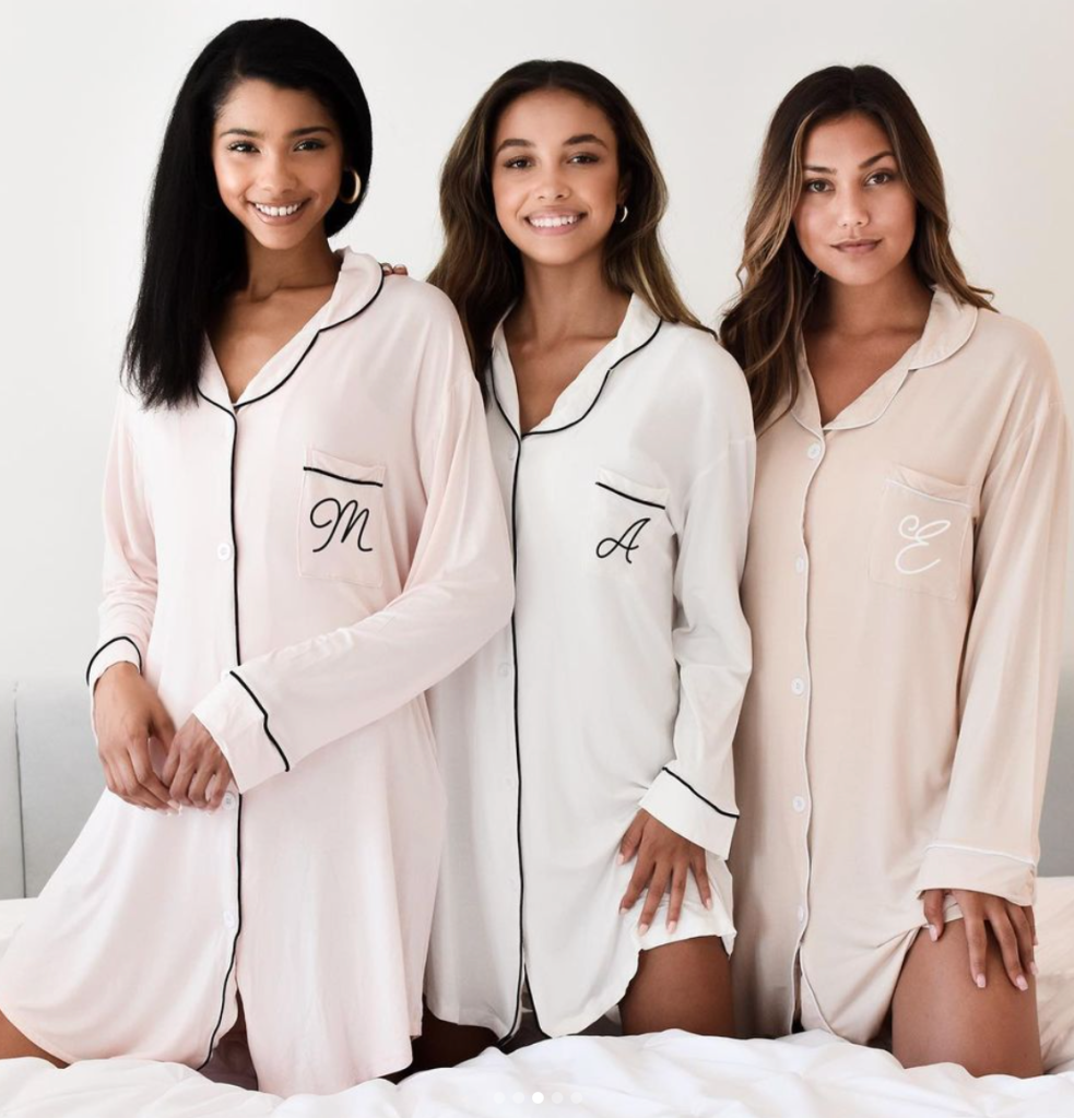 In questa foto tre ragazze sorridenti indossano camicie da notte per addio al nubilato con le iniziali di ciascuna 