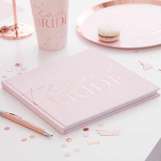 In questa foto un gustbook di colore rosa per addio al nubilato con scritto Team Bride