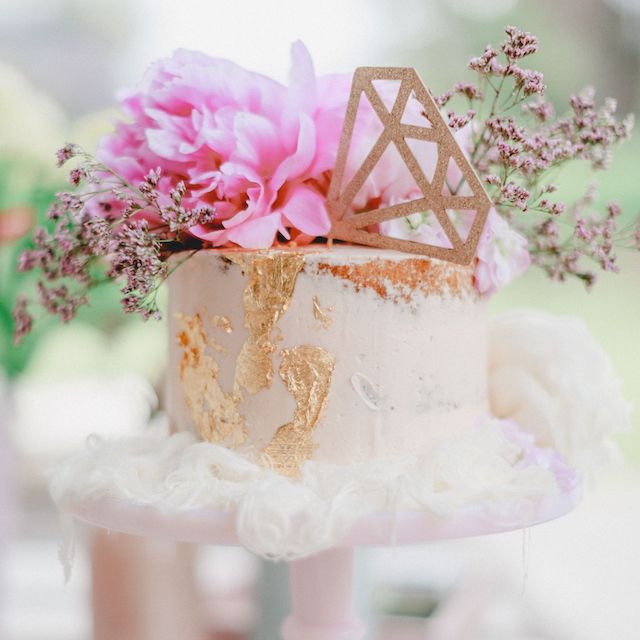 In questa foto una torta per addio al nubilato con fiori freschi e una decorazione a forma di anello colore oro