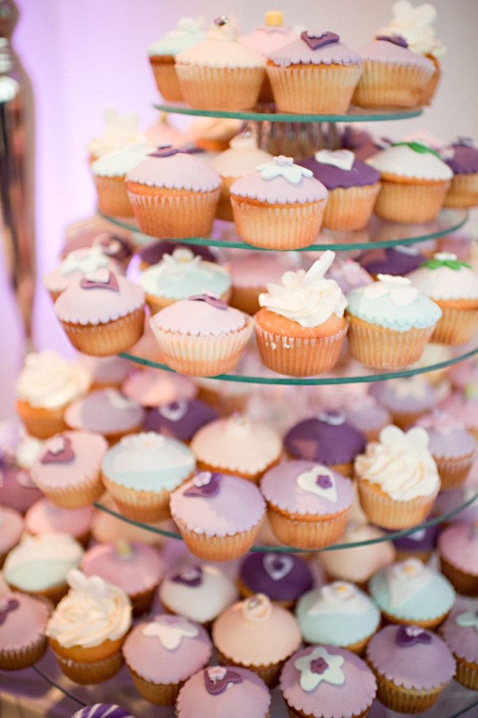 In questa foto una torre di cupcake nei colori del lilla, viola e rosa