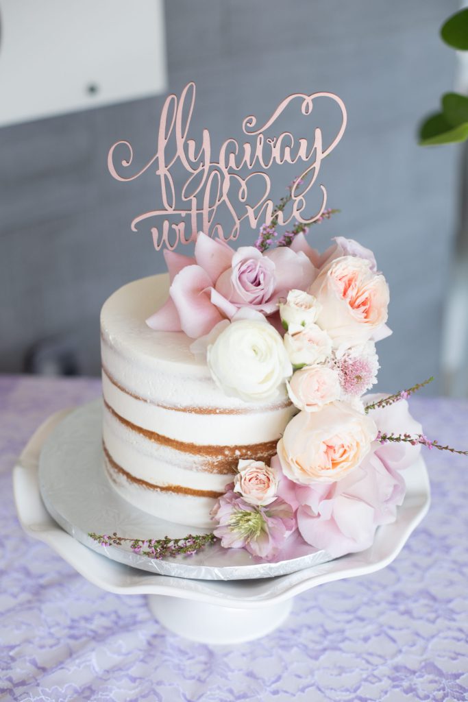 In questa foto una naked cake con fiori freschi di colore rosa e bianco