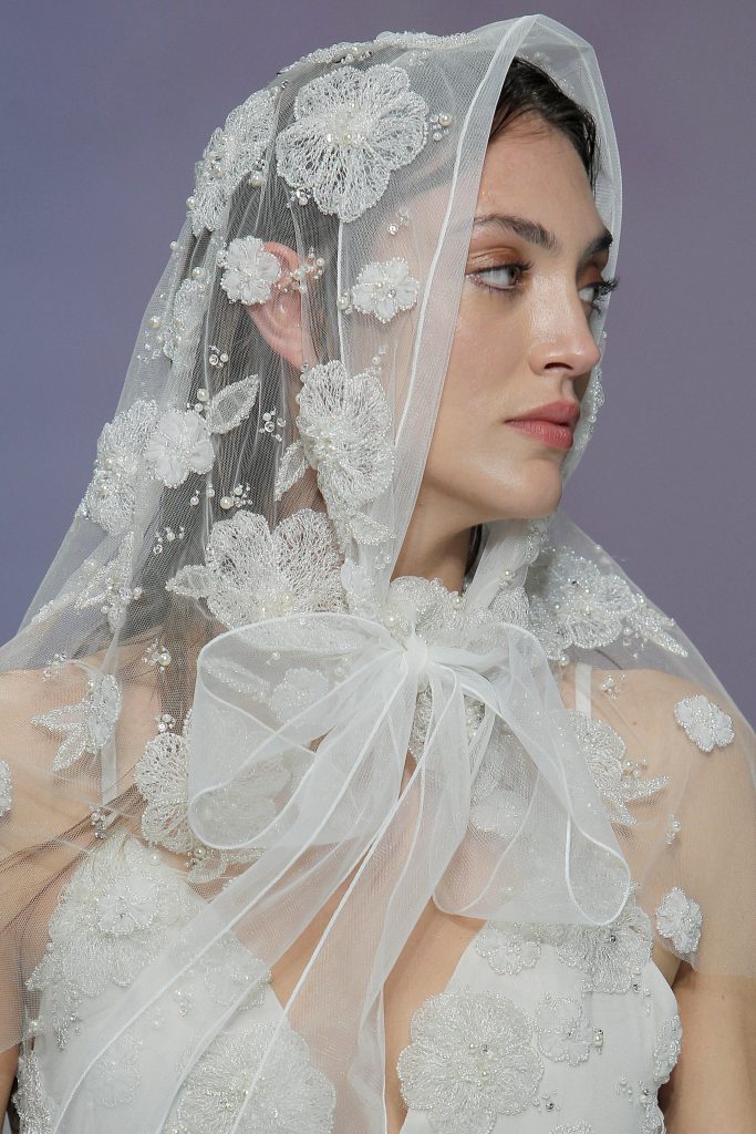 In questa foto una modella indossa un velo da sposa con fiori ricamati.