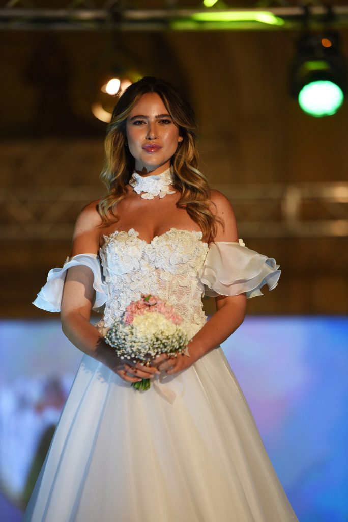 In questa foto uno degli abiti da sposa presentati durante l'evento di Polisano Spose: bustino in pizzo, gonna morbida ampia e maniche