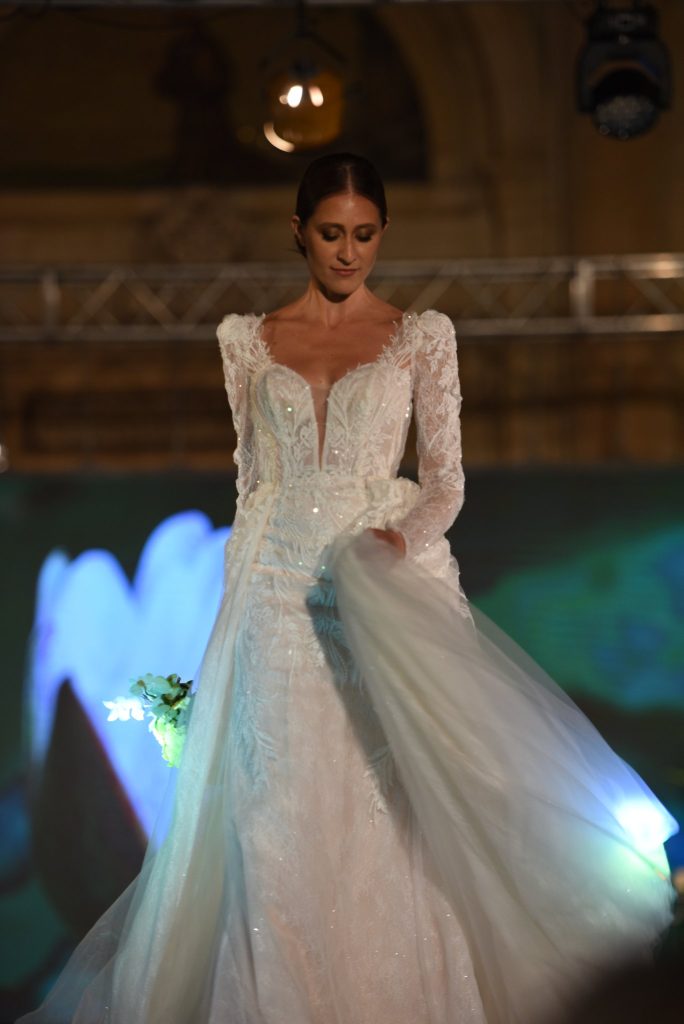 In questa foto uno degli abiti da sposa presentati all'evento di Polisano Spose: coda rimovibile e maniche lunghe in pizzo