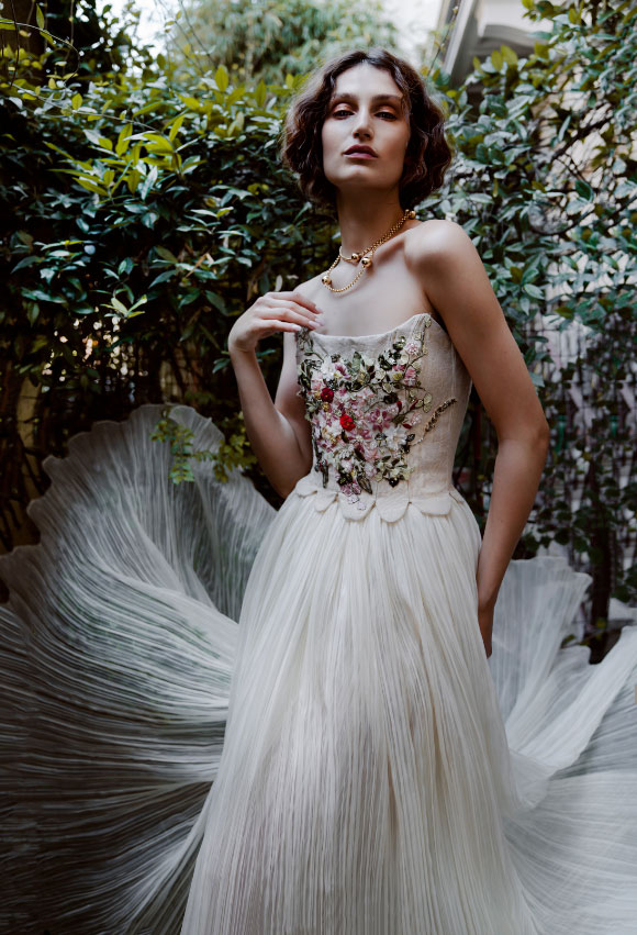 In questa foto una modella in un giardino, mentre indossa uno degli abiti da sposa 2023 di Elisabetta Delogu