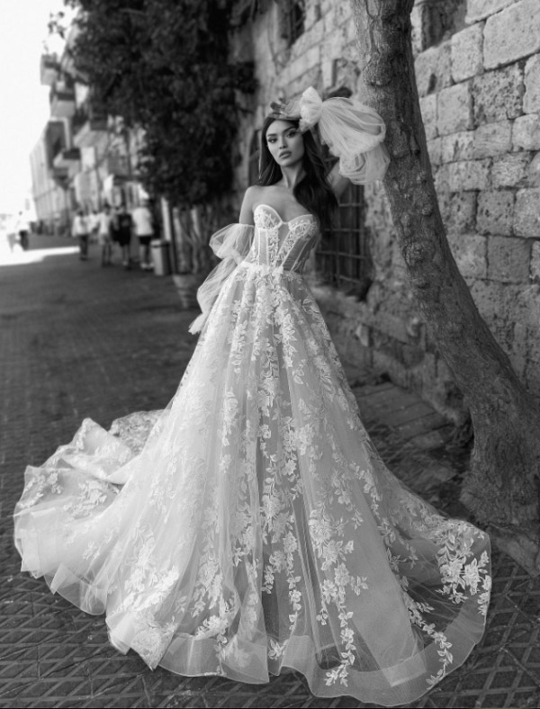 In questa foto una modella indossa un abito da sposa con bustier e in pizzo floreale della collezione Julie Vino 2023