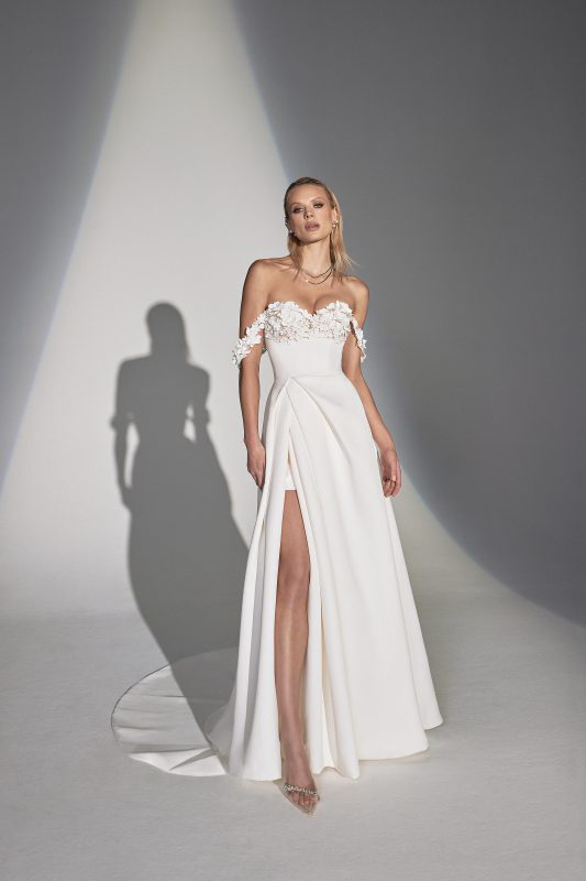 In questa foto una modella indossa un abito da sposa Justin Alexander 2023: il modello è scivolato, con applicazioni floreali sul decollete e un profondo spacco