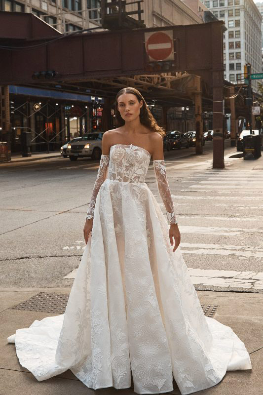 In questa foto una modella cammina per le strade di New York con indosso un abito da sposa La Premiere Bridal 2023
