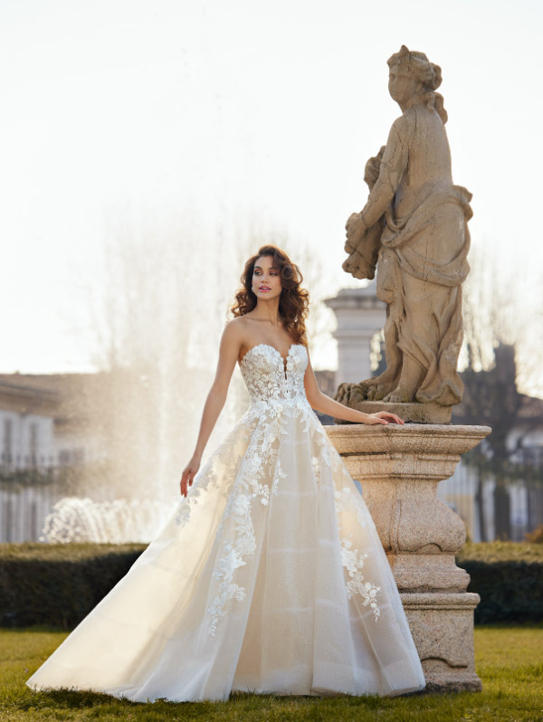 In questa foto una modella indossa un abito da sposa della collezione Randy Fenoli 2023