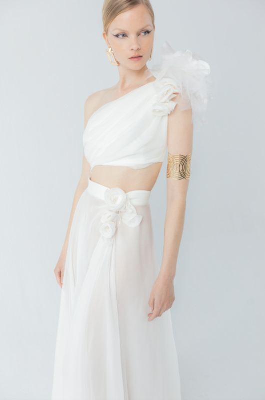 In questa foto una modella con un abito da sposa monospalla, modello crop top, della collezione 2023 del  brand YolanCris 