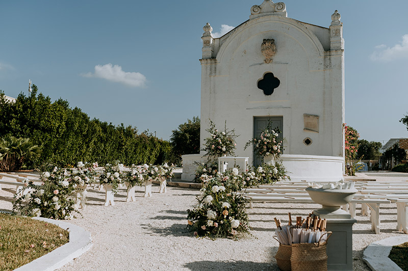 In questa foto la chiesetta bianca allestita per le nozze di Soha ed Anthony con panche bianche e composizioni floreali sui toni bianco e verde