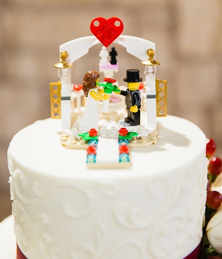 In questa foto, una torta nuziale con un cake topper realizzato con mattoncini Lego e due minifigure sposi 