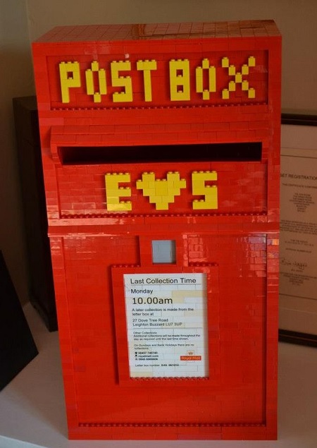 In questa foto, una cassetta della posta realizzata con mattoncini rossi e scritta gialla 