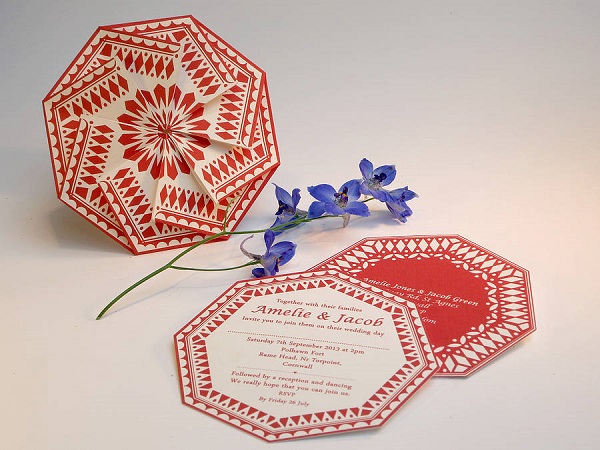 In questa foto, partecipazioni matrimonio originali a forma di ottagono con doppio biglietto e chiusura origami nei toni del crema e del rosso corallo