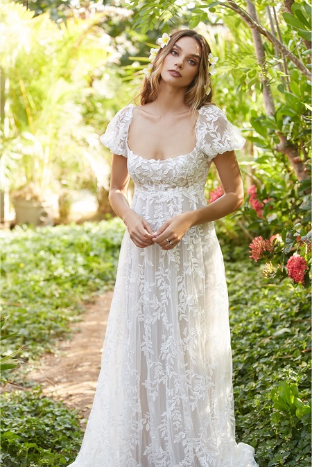 In questa foto, una sposa con un abito in stile impero in organza ricamata con taglio sotto al seno, maniche a palloncino e gonna lunga morbida modello indicato per un matrimonio stile Bridgerton