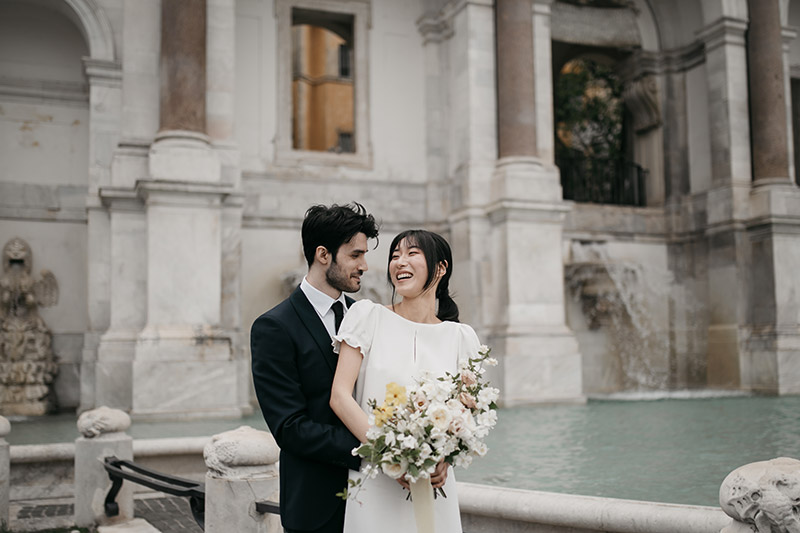 in questa foto una coppia di sposi davanti alla Fontana di Trevi per un destination wedding a Roma