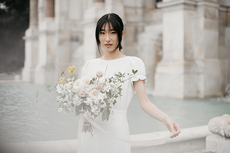In questa foto una sposa di origini asiatici alla Fontana di Trevi tiene tra le mani un bouquet selvaggio realizzato da Sara Tusset Floral Designer 