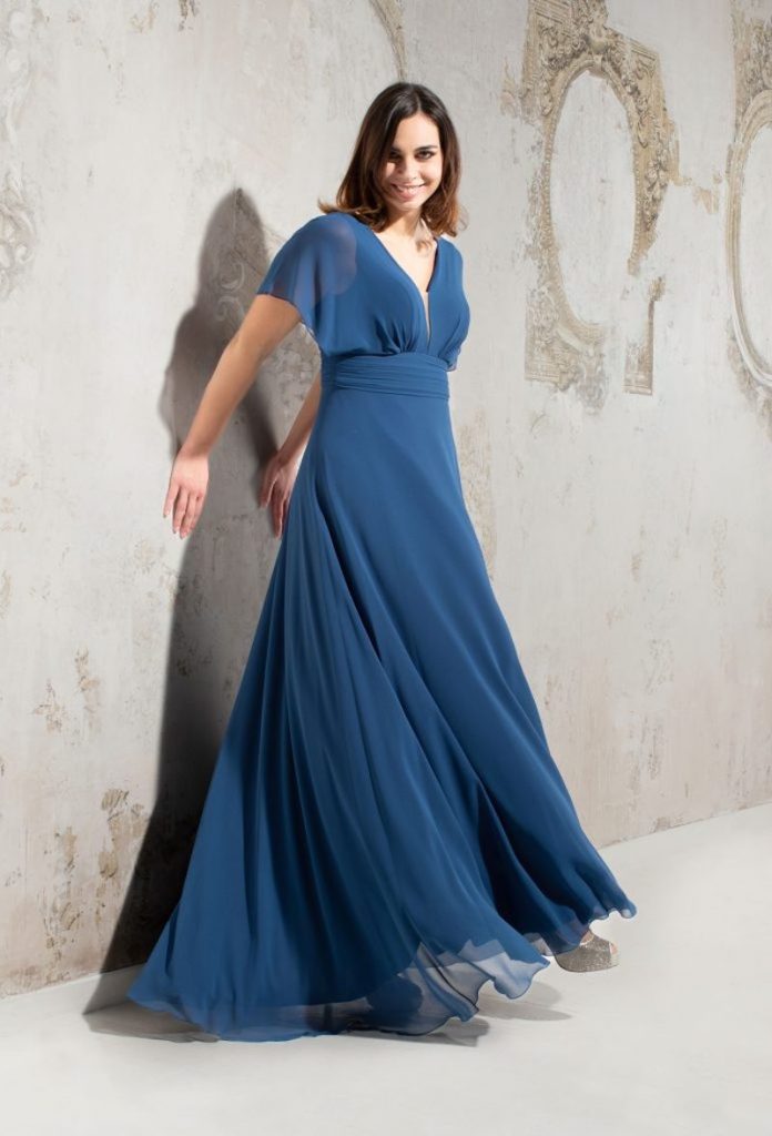 In questa foto una modella indossa un  abito da cerimonia per donne curvy modello impero di Musani in chiffon di colore azzurro