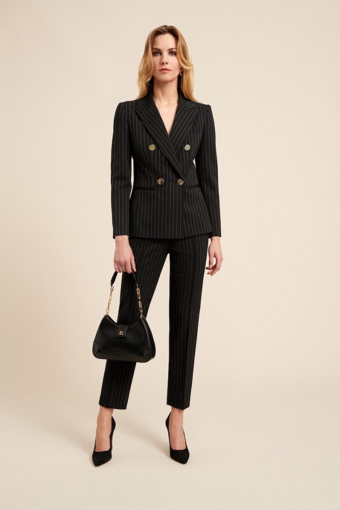 In questa foto una modella indossa un   abito da cerimonia con pantaloni Capri e giacca doppiopetto in tessuto gessato nero di Luisa Spagnoli